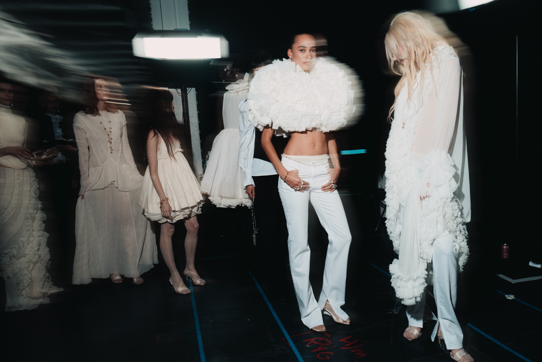 Models in white ruffled and lace looks backstage at H&M’s London Fashion Week show